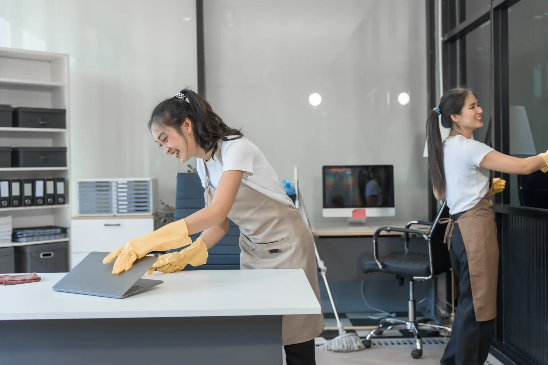 Woman cleaning a table with gloves in a modern office.